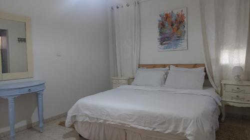 a white bedroom with a bed and a mirror at וילה בת גליל יסוד המעלה in Yesod Hamaala