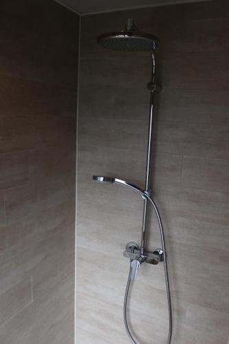 La salle de bains est pourvue d'un pommeau de douche et de carrelage. dans l'établissement Le Manoir de l'Abbaye, à Saverne