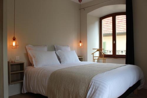 a bedroom with a bed with white sheets and a window at Le Manoir de l'Abbaye in Saverne