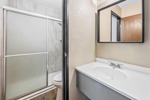 a bathroom with a sink and a toilet and a mirror at Super 8 by Wyndham Colorado Springs Peterson Space Force in Cimarron Hills