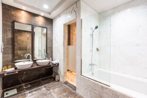 a bathroom with two sinks and a shower and a tub at Rixos The Palm Hotel & Suites - Ultra All Inclusive in Dubai