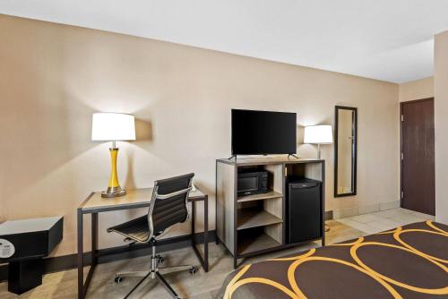 a hotel room with a bed and a desk and a television at Super 8 by Wyndham Terre Haute in Terre Haute
