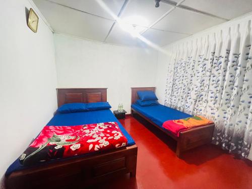a bedroom with two beds and a curtain at Liptora Homestay in Bandarawela