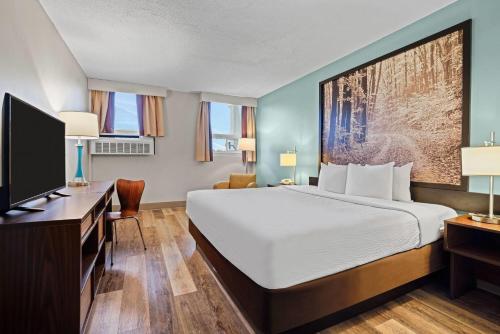 a hotel room with a bed and a flat screen tv at Super 8 by Wyndham Thunder Bay in Thunder Bay
