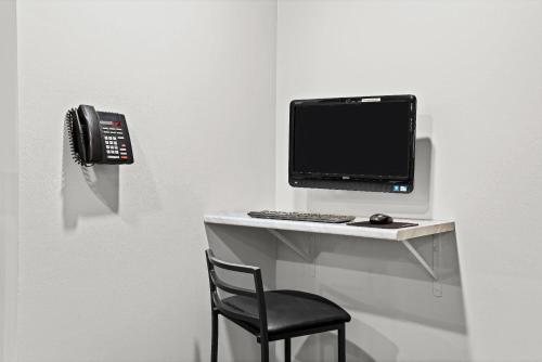 a computer on a desk with a chair and a phone at Super 8 by Wyndham Thunder Bay in Thunder Bay