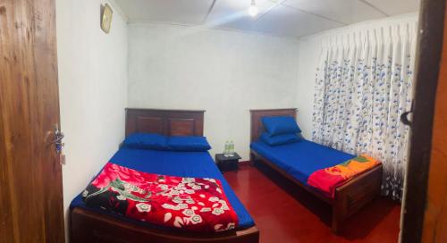 a bedroom with two beds with blue and red sheets at Liptora Homestay in Bandarawela