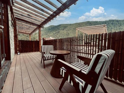 a deck with two chairs and a table and a table at Mid Hill White Lodge in Mount Siguniang