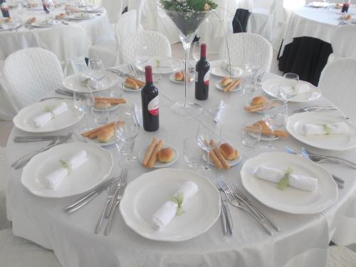 a white table with white plates and wine bottles at Agriturcostabaira in Caltagirone