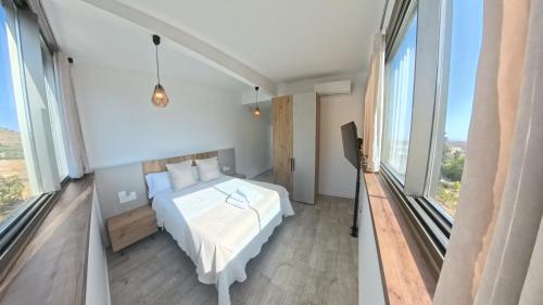 a bedroom with a white bed and large windows at Mirasierra in Mancha Real