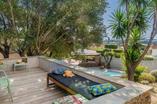 un patio con una panchina su un ponte di legno con alberi di Villa Le Corps de Garde a Furiani