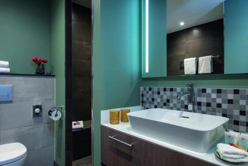 a bathroom with a sink and a toilet at Leonardo Royal Hotel Amsterdam in Amsterdam