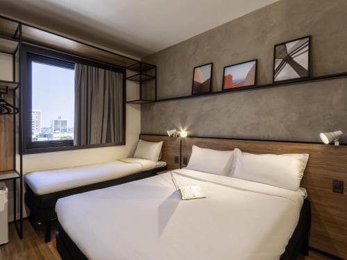 a hotel room with two beds and a window at ibis Ponta Grossa in Ponta Grossa