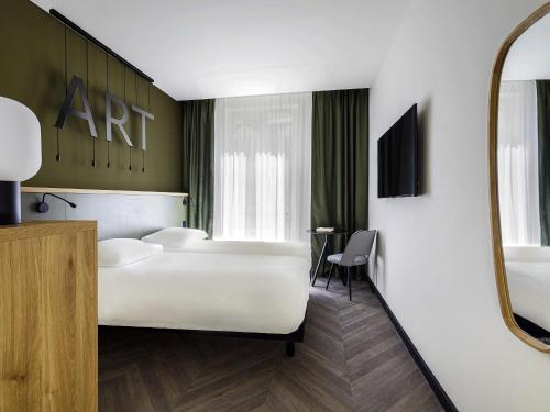 a hotel room with a white bed and a mirror at Mercure Grand Hôtel Metz Centre Cathédrale in Metz