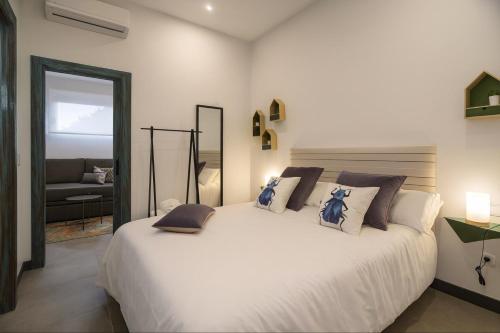 a bedroom with a large white bed with pillows at TRIA NOMINA Apartamentos Turísticos in Mérida