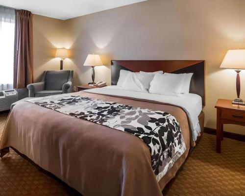 a hotel room with a large bed and a chair at Rodeway Inn & Suites Salina South in Salina