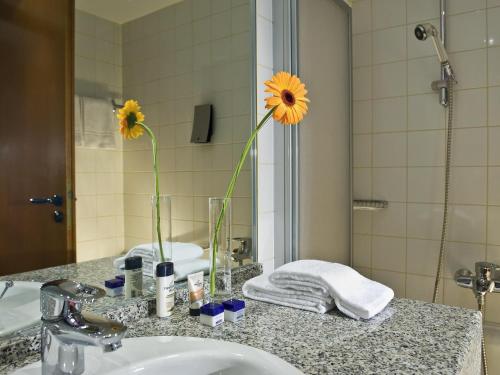 a bathroom sink with a vase with a flower in it at Congress Hotel Weimar by Mercure in Weimar
