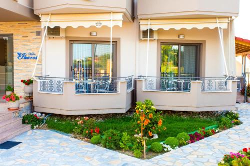 a house with a balcony and flowers in the yard at Villa Ikaros in Ammoudia