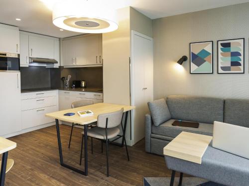 a kitchen and living room with a table and a couch at Aparthotel Adagio London Stratford in London