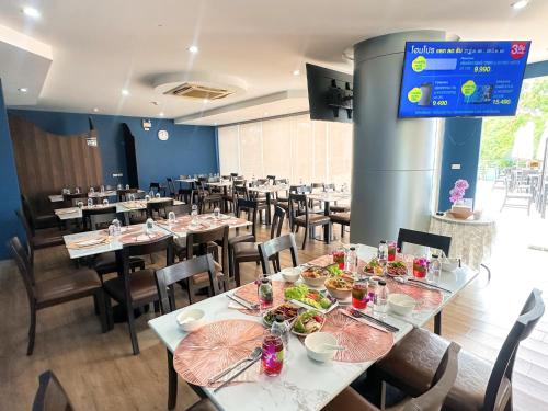 a dining room with tables and chairs and a tv at Anna-Nava Pakkret Hotel in Nonthaburi