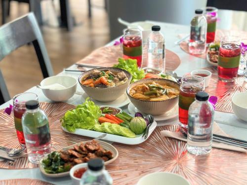 a table topped with bowls of food and vegetables at Anna-Nava Pakkret Hotel in Nonthaburi