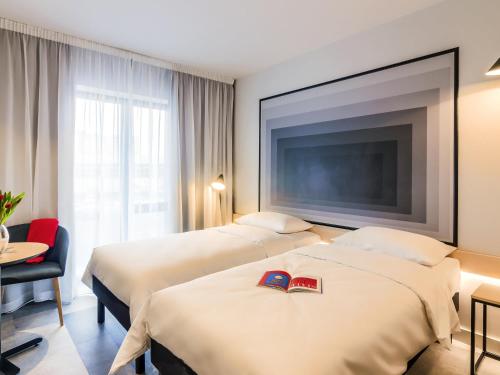 a hotel room with two beds and a flat screen tv at ibis Timisoara City Center in Timişoara