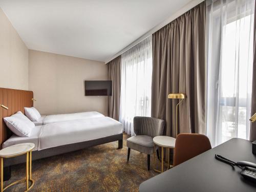 a hotel room with a bed and a window at Mercure Bialystok in Białystok