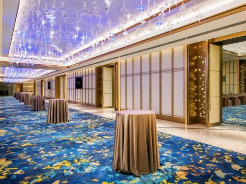 a row of tables in a room with a blue carpet at Pullman Foshan Shunde-Canton Fair Shuttle Bus at Extra RMB100 per Person Daily in Shunde