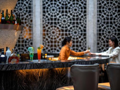 two women standing at a bar in a restaurant at Pullman Foshan Shunde-Canton Fair Shuttle Bus at Extra RMB100 per Person Daily in Shunde
