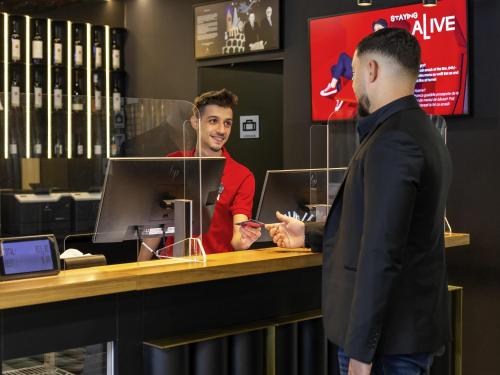 a man talking to a customer at a counter at ibis Bucharest Politehnica in Bucharest