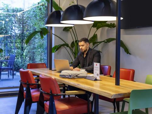 a man sitting at a table with a laptop at ibis Bucharest Politehnica in Bucharest