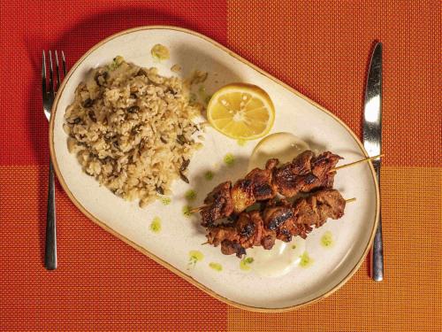 a plate of food with rice and meat and a lemon at ibis Bucharest Politehnica in Bucharest