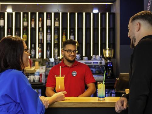 a group of people standing around a bar with a drink at ibis Bucharest Politehnica in Bucharest