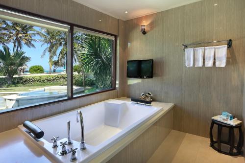 a large bathroom with a large tub and a window at Novotel Lombok Resort & Villas in Kuta Lombok