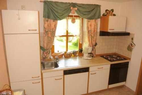 cocina con nevera blanca y ventana en Haus Am Waldrand - Ferienwohnung Augustin, en Grafenau
