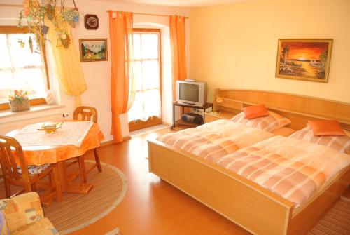 um quarto com uma cama, uma mesa e uma televisão em Haus Am Waldrand - Ferienwohnung Augustin em Grafenau