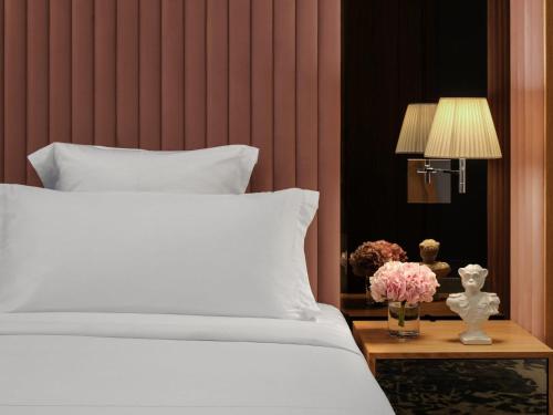 a bedroom with a white bed and a table with flowers at SLS Dubai Hotel & Residences in Dubai