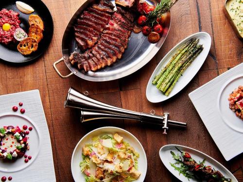 a table topped with plates of food with meat and vegetables at SLS Dubai Hotel & Residences in Dubai
