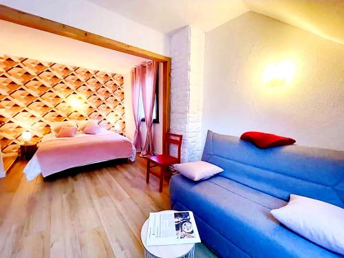 a living room with a blue couch and a bed at Domaine de la Papeterie in Glay