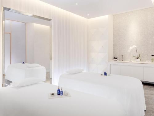 two beds in a white room with a mirror at SLS Dubai Hotel & Residences in Dubai