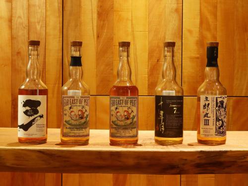 four bottles of whisky sitting on a wooden shelf at 湯の里いけもり別館 天座 in Himi