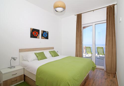 a bedroom with a bed with a green blanket and a window at Vista Apartments in Cavtat