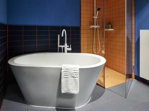 a bath tub in a bathroom with a shower at 25hours Hotel Hamburg HafenCity in Hamburg