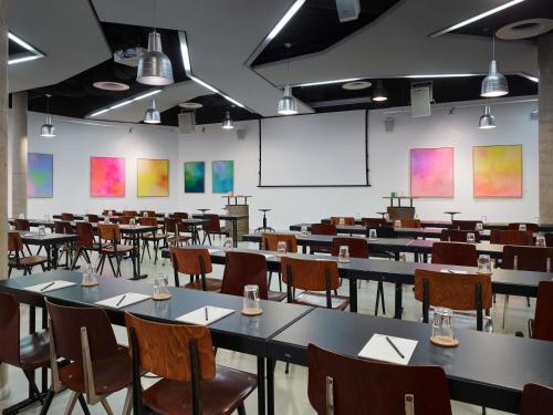 an empty classroom with tables and chairs and a whiteboard at 25hours Hotel Hamburg HafenCity in Hamburg