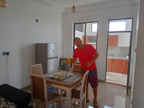 a man standing at a table in a kitchen at J's lodge in Negombo