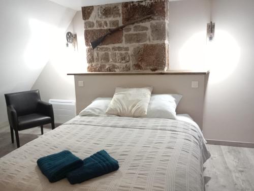a bedroom with a bed with two blue pillows on it at Gîte Le Mansois in Marcillac-Vallon