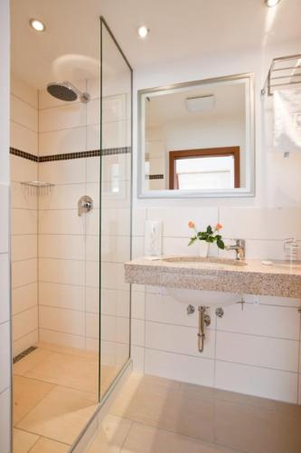 a bathroom with a shower and a sink and a mirror at Hotel Carlton in Duisburg