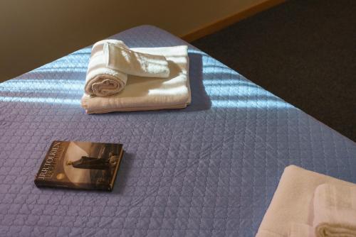 a bed with a towel and a book on it at Rooster Hotel in Sanguinetto