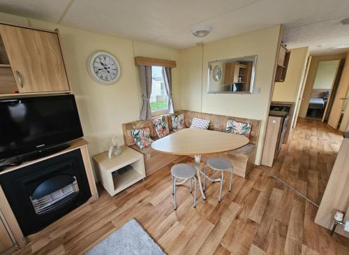 a living room with a table and a tv at Caravan Meg 3 bed robin holiday in Rhyl