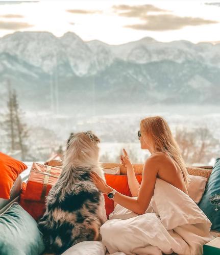 two women sitting on a couch with a dog at Osada Gubałówka na Polanie Pająkówka & SPA in Kościelisko