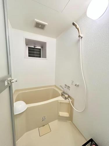 a white bathroom with a sink and a shower at 女性専用ゲストハウス与那原 in Yonabaru